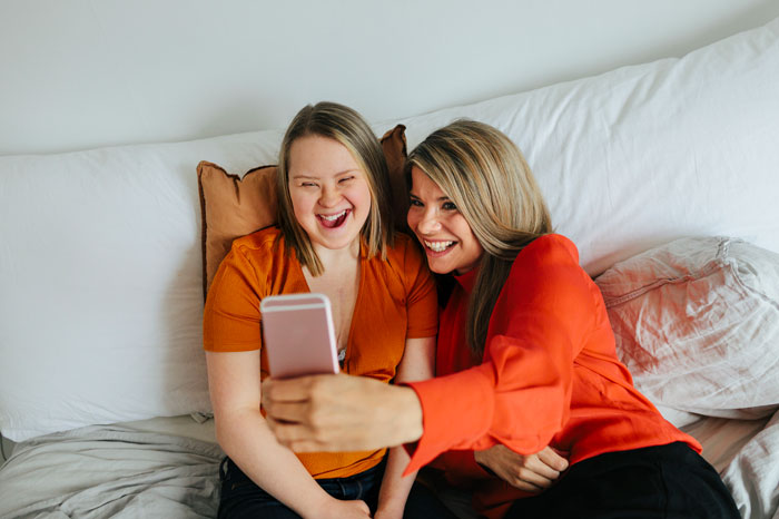 two people sitting on a sofa looking at a mobile phone