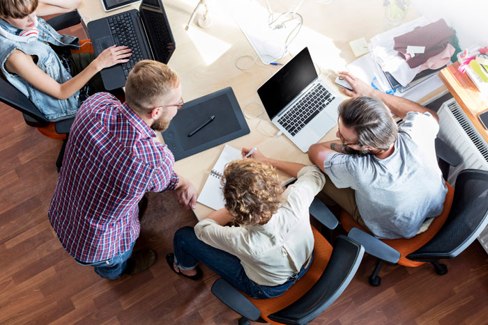 people sitting round a table with laptops