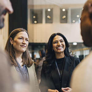 Glada affärskvinnor pratar med andra representanter på event